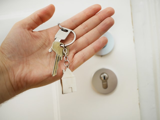 Hand holding a key connected to a house-shaped keychain